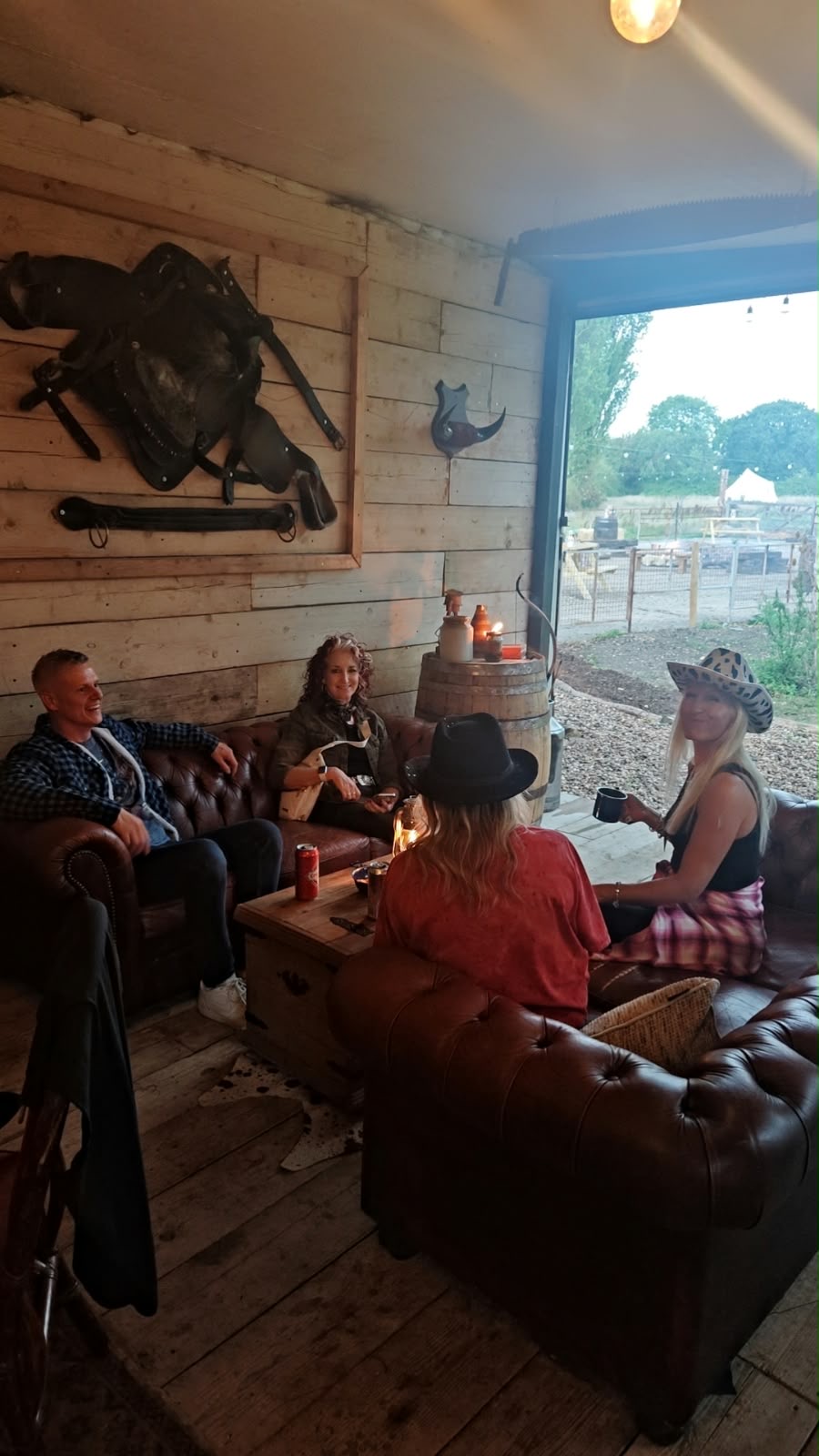 A group of colleagues talking on leather sofas in the saloon, doors open onto the yard